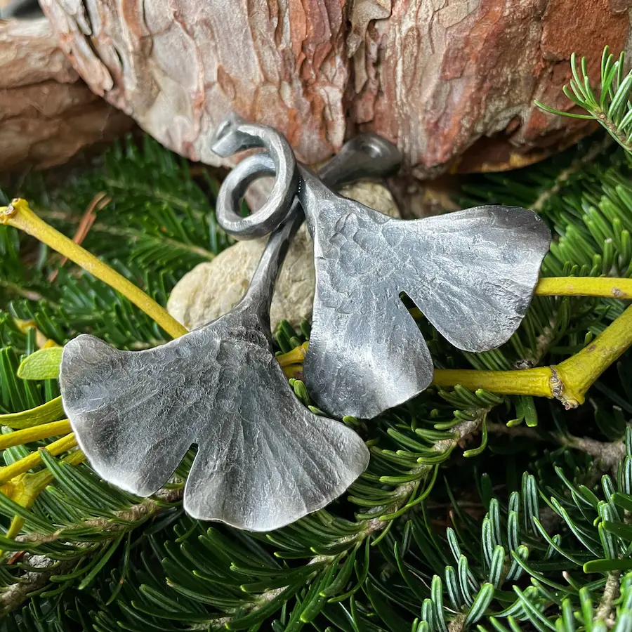 Zwei handgeschmiedete Ginkgoblätter aus Stahl - auf Mistel- und Tannenzweigen drapiert