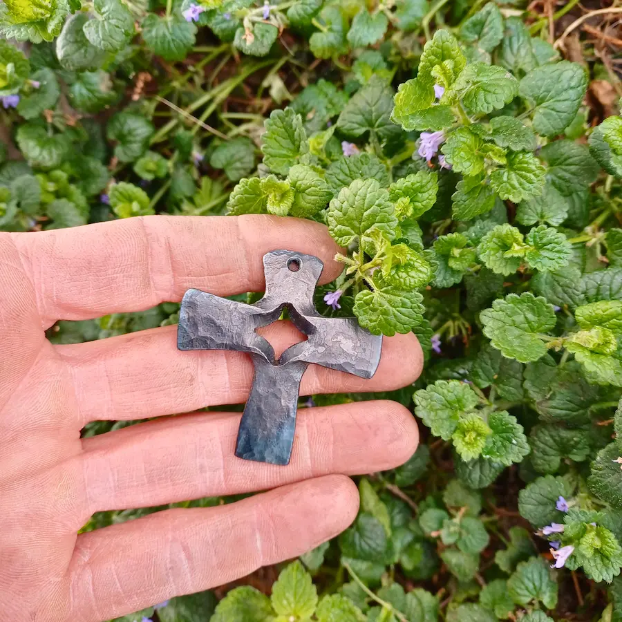 Handgeschmiedetes und gespaltenes Schmuckkreuz auf Hand platziert als Größenvergleich